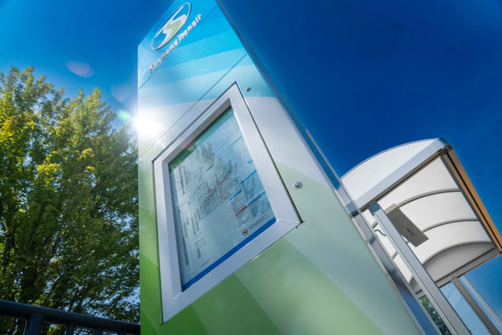 Smart map kiosk at a transit station with blue sky and tree in the background.