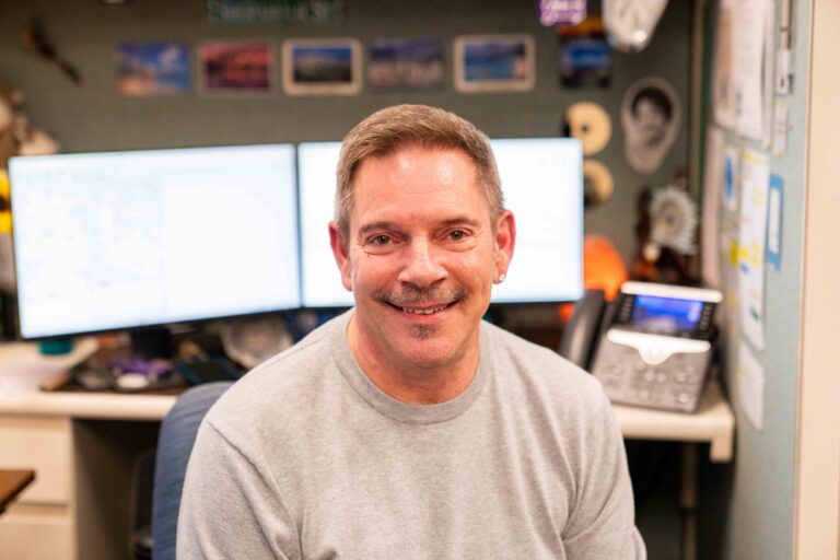 Toby Herman smiles in front of his work station at the Paratransit reservation office.