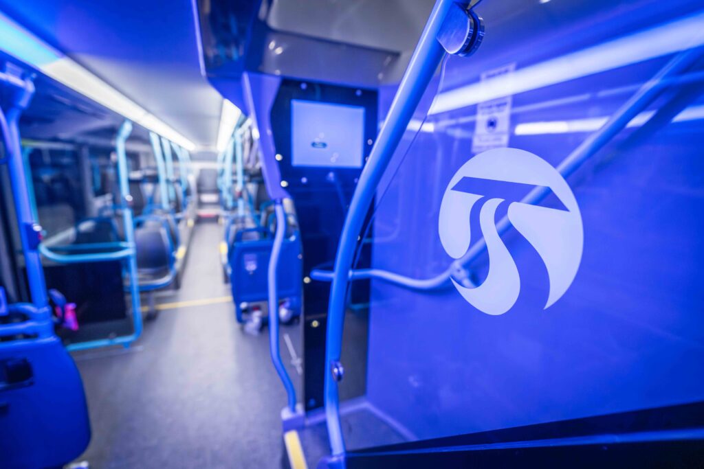 STA bus interior, blue lighting, transit logo on glass panel.