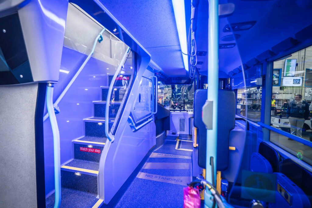 Double-decker STA bus interior, blue lighting, stairs to upper level.