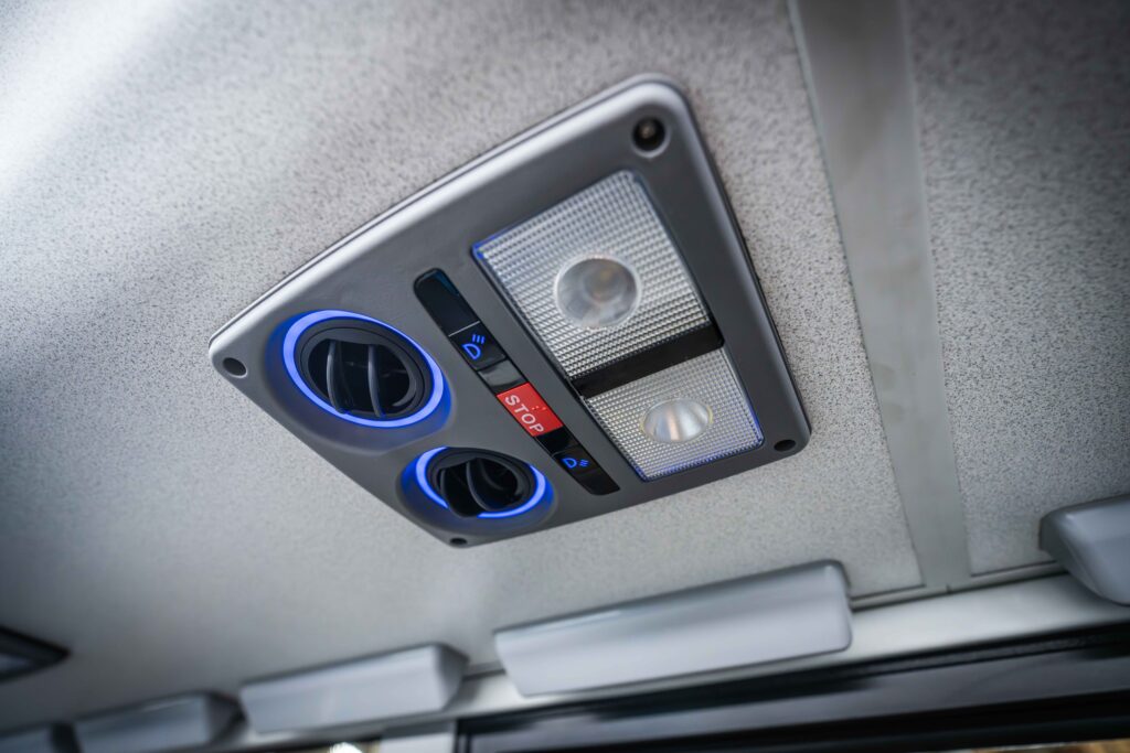 STA bus ceiling panel with air vents, lights, and red "STOP" button.