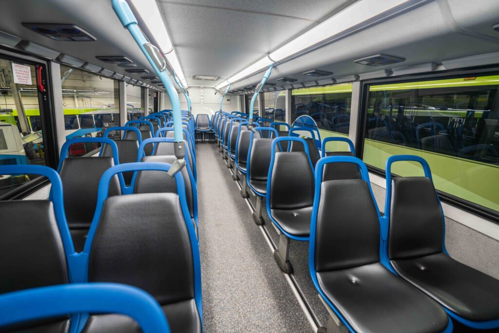 Empty STA bus interior, black seats, blue handrails, front-to-back view.