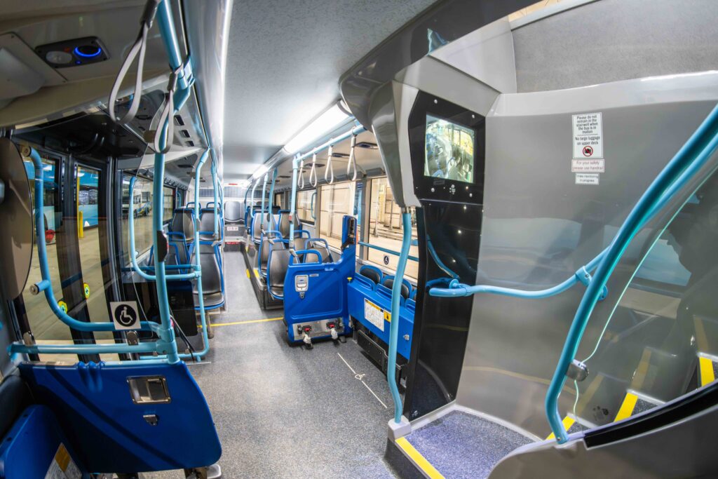 STA double decker bus interior with blue handrails, blue seats, and designated wheelchair area.