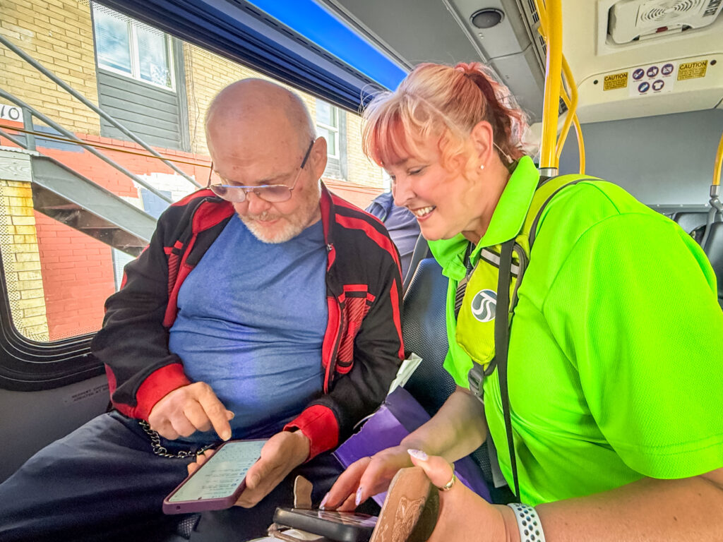 Transit Ambassador Tammy assists a rider onboard Route 4 after passing out promo gift bags in celebration of the Monroe and Summit bus shelter opening.