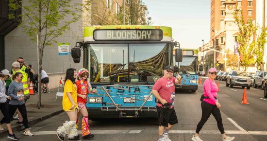 a group of Bloomsday runners walk by an STA bus.